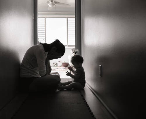 Sad and tired mother with her baby girl at home.